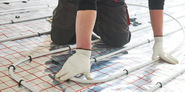 Engineer installing wet underfloor heating pipes using staples.